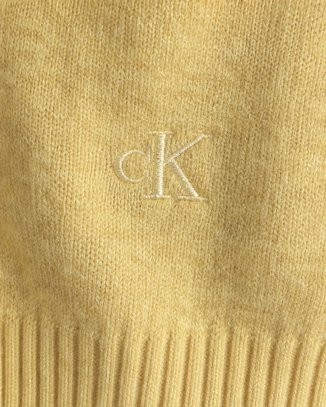 Colour: Pale Ochre | Close-up of embroidered CK logo and knit texture